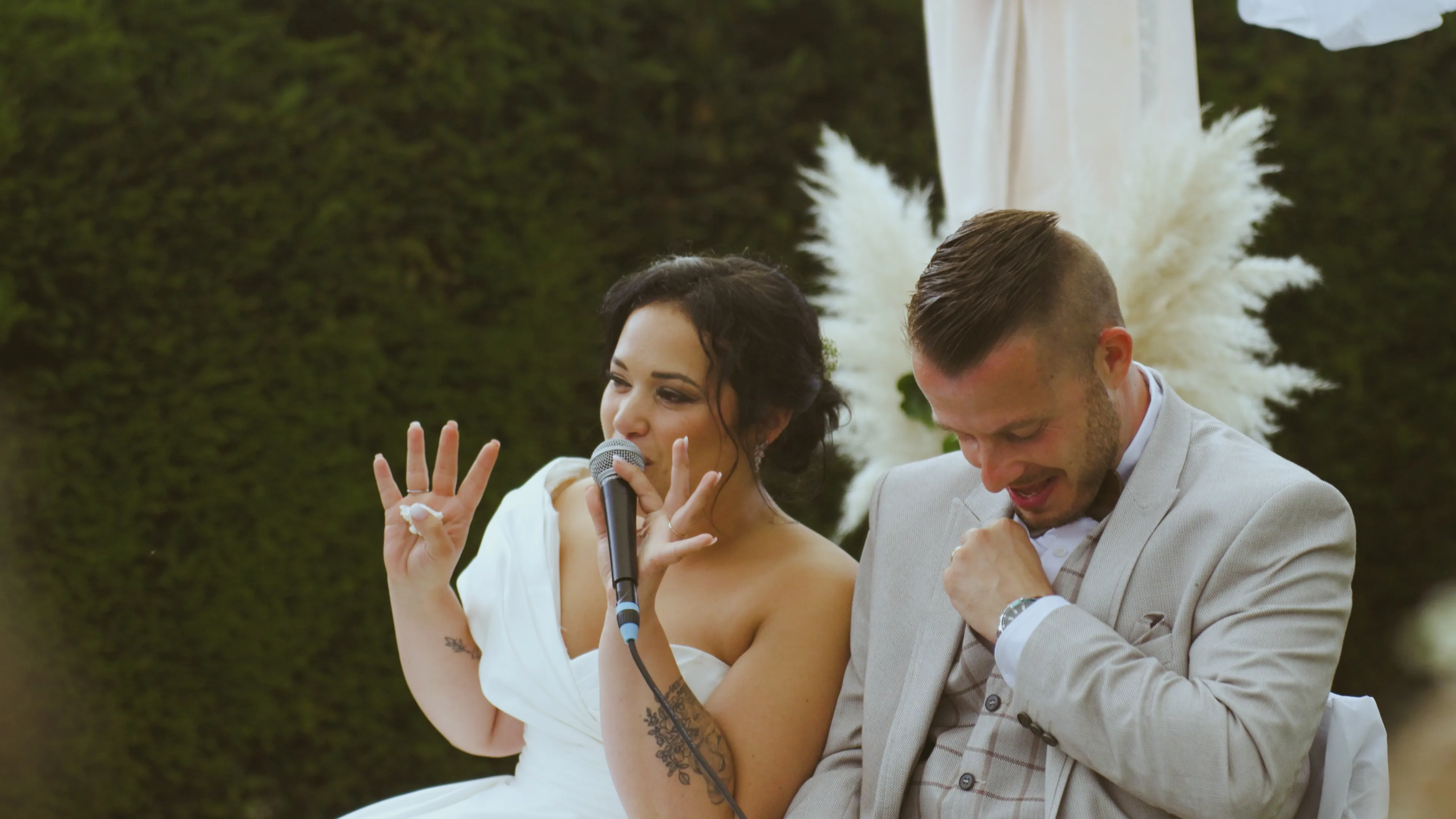 deux jeunes mariés sont assis l'un à côté de l'autre - la mariée parle dans un micro, son mari rigole