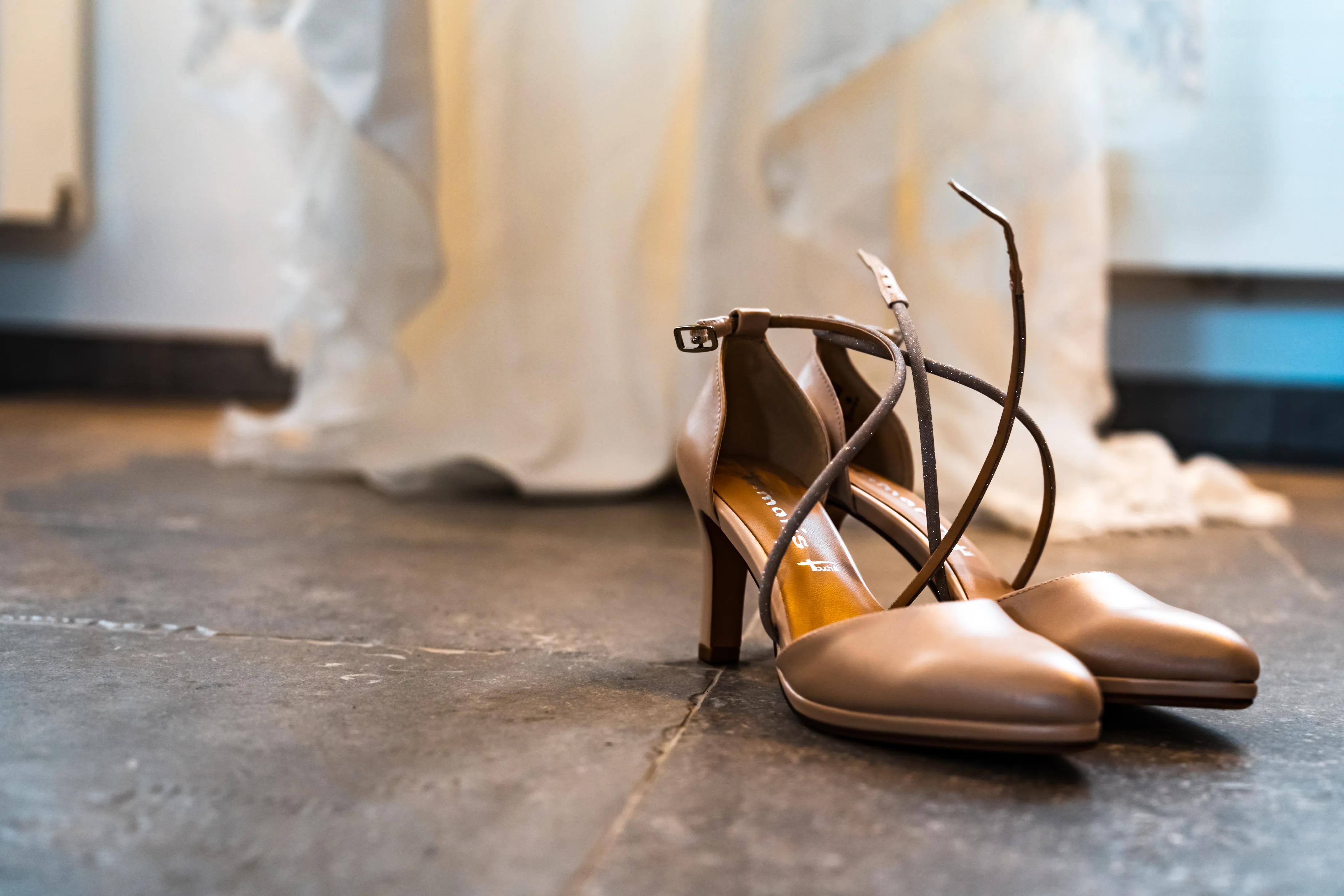 une paire de talons hauts sont placées devant une robe de mariée