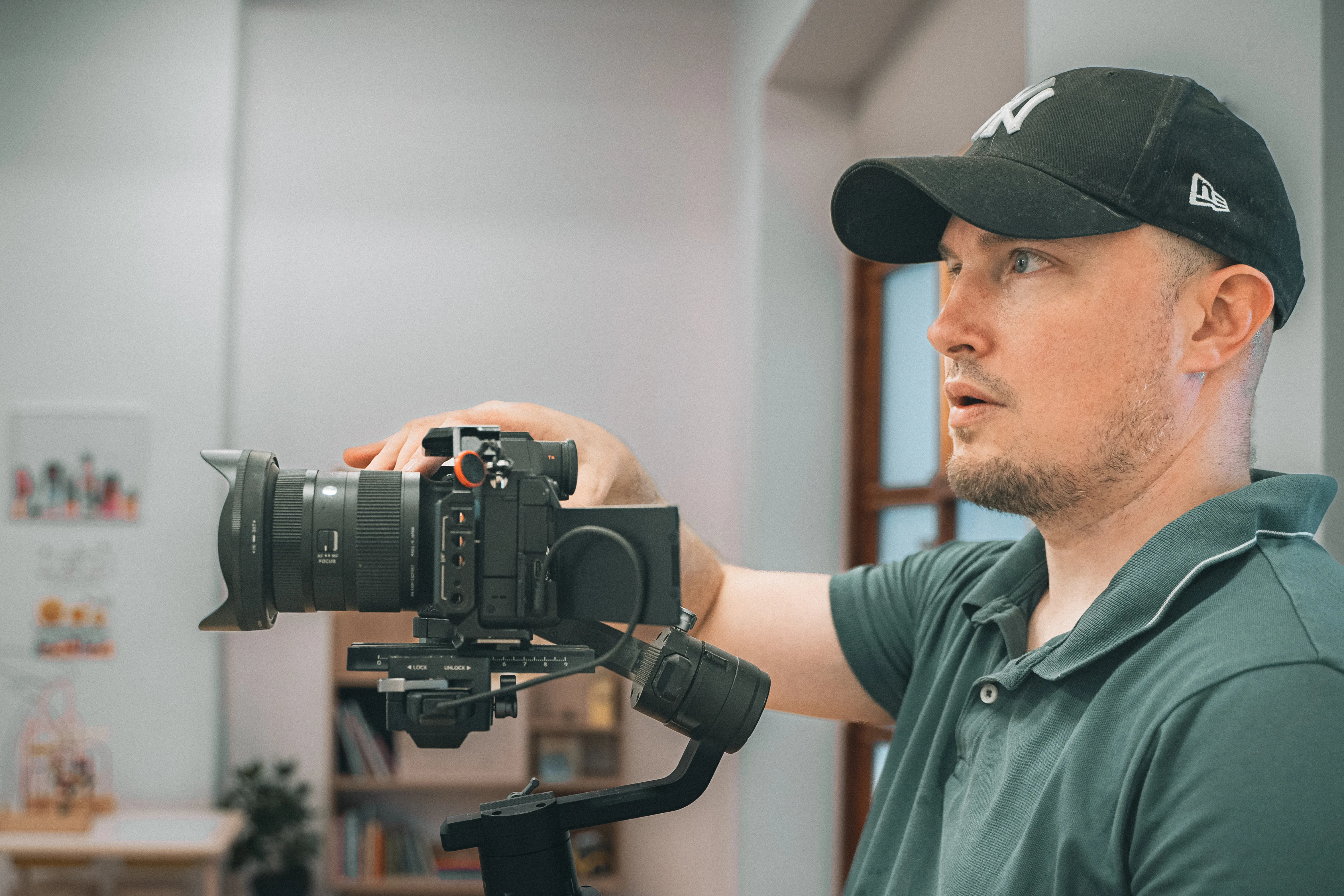 un homme avec une casquette est vu de profil, derrière un appareil photo