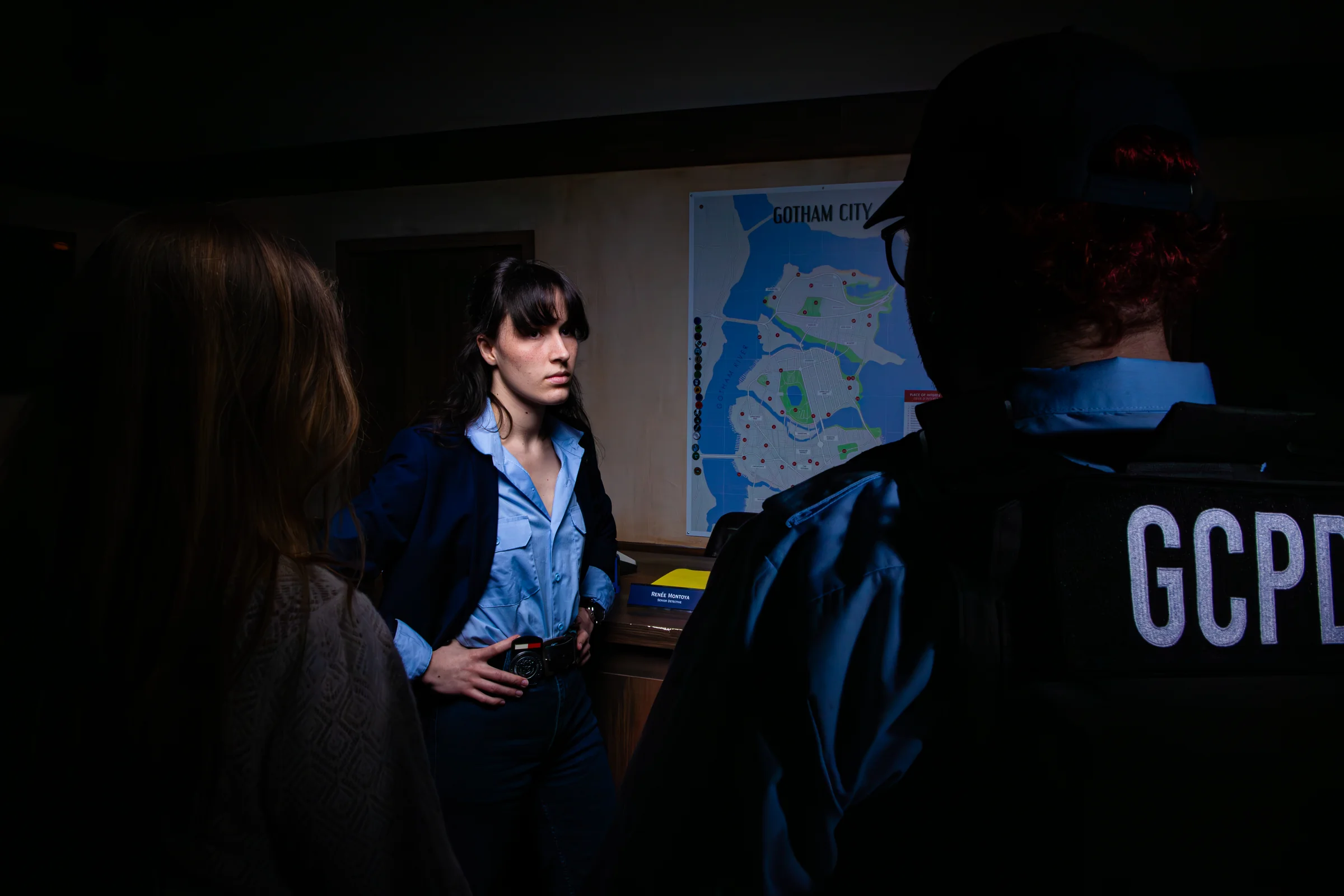 Bureau d'enquête du commissariat de Gotham avec lampe verte et vue sur la ville — escape game enquête immersif à Paris