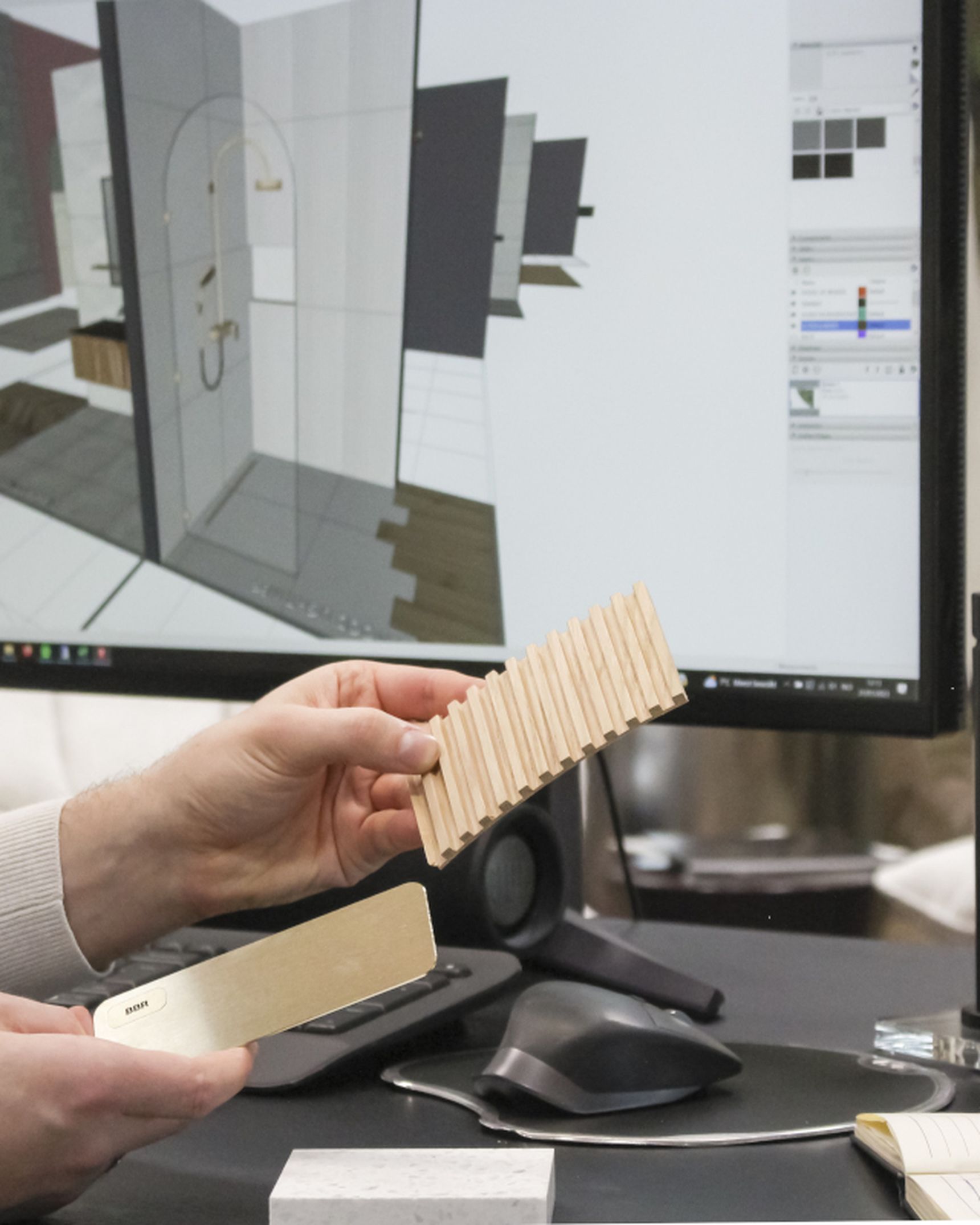 Pieter houdt houtstalen vast aan een bureau met computer waarop een 3D-interieurontwerp zichtbaar is.