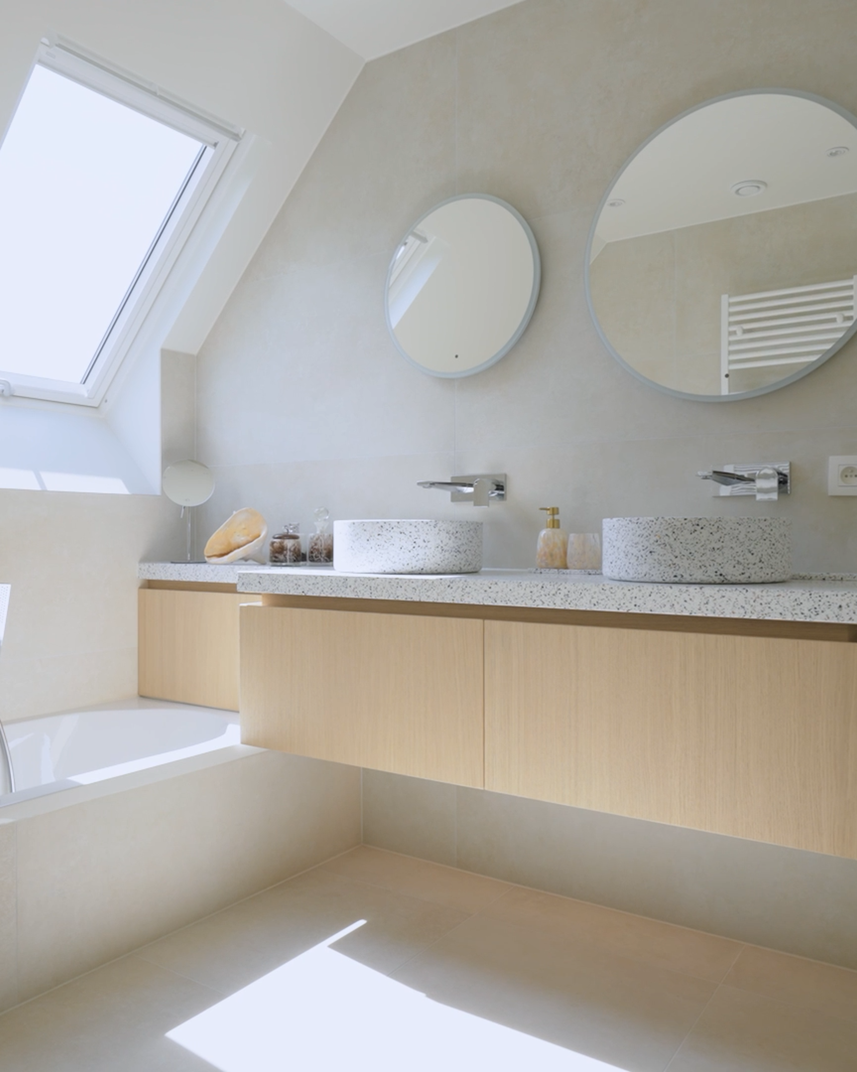 Modern bathroom with two round mirrors, dual sinks on a floating wooden vanity, a bathtub, and a skylight illuminating the space.