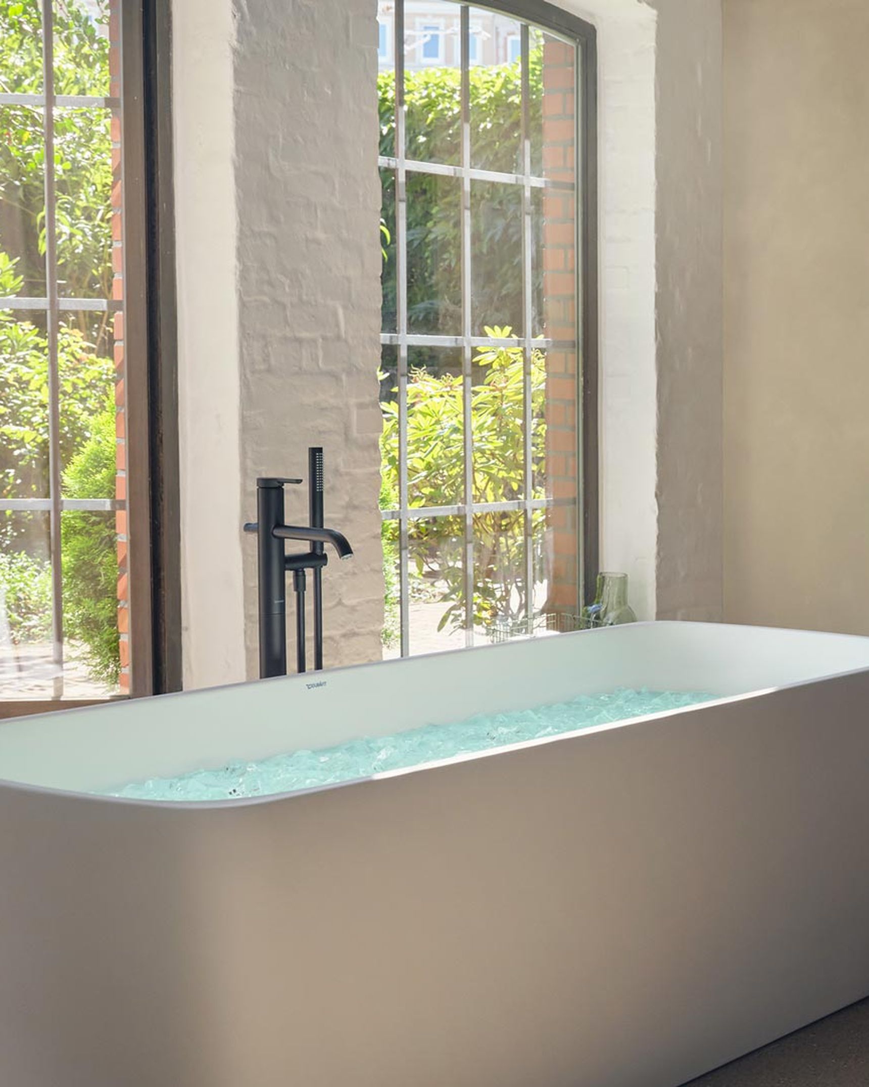 Modern badkamer met vrijstaand champagnebubbelbad en wastafelmeubel, met een man die zich klaarmaakt naast het bad.