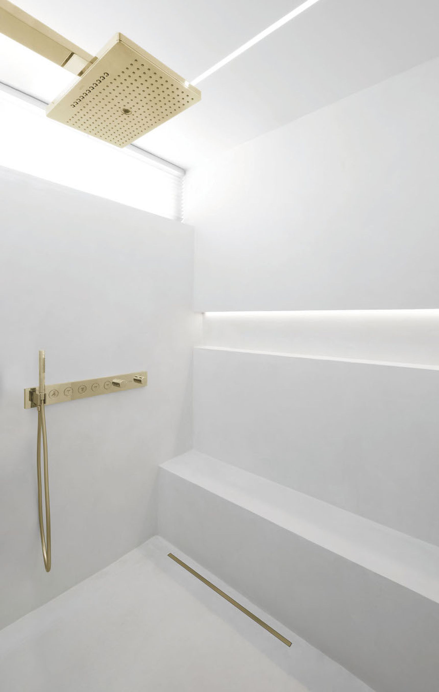 Minimalist white shower with gold fixtures, including a rainfall showerhead and handheld spray, set against sleek, modern design elements.