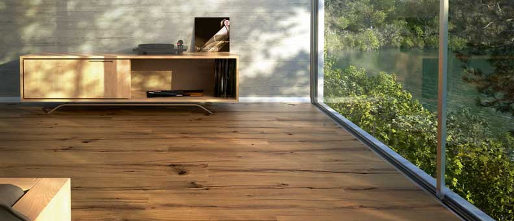 Moderne leefruimte met houten vloer, grote glaspartijen met uitzicht op het bos en minimalistisch houten dressoir tegen een betonnen wand.