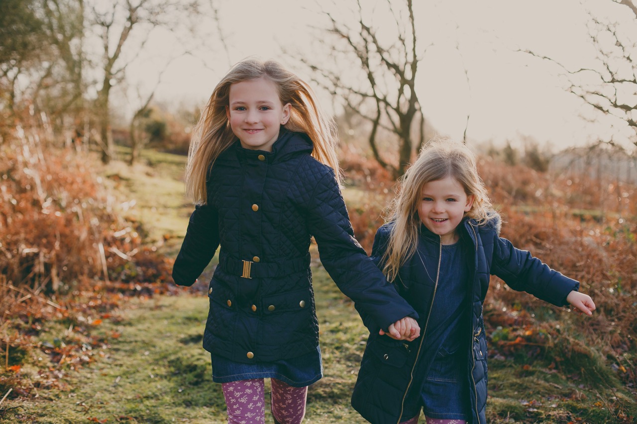 Twee meisjes buiten rennen met jas aan