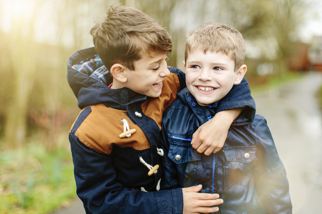 Twee jongens met jas aan aan het knuffelen buiten