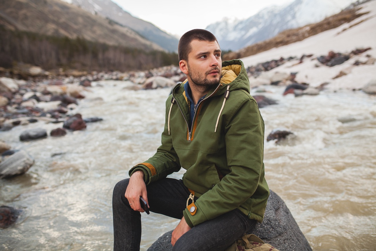 Man met een canvas jas in de bergen