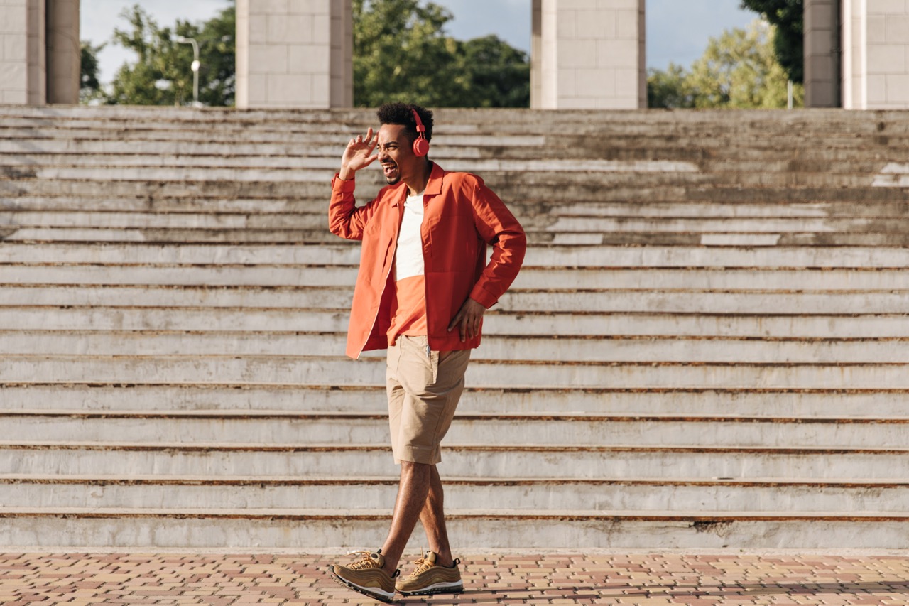 Vrolijke man in beige shorts en oranje zomerjas