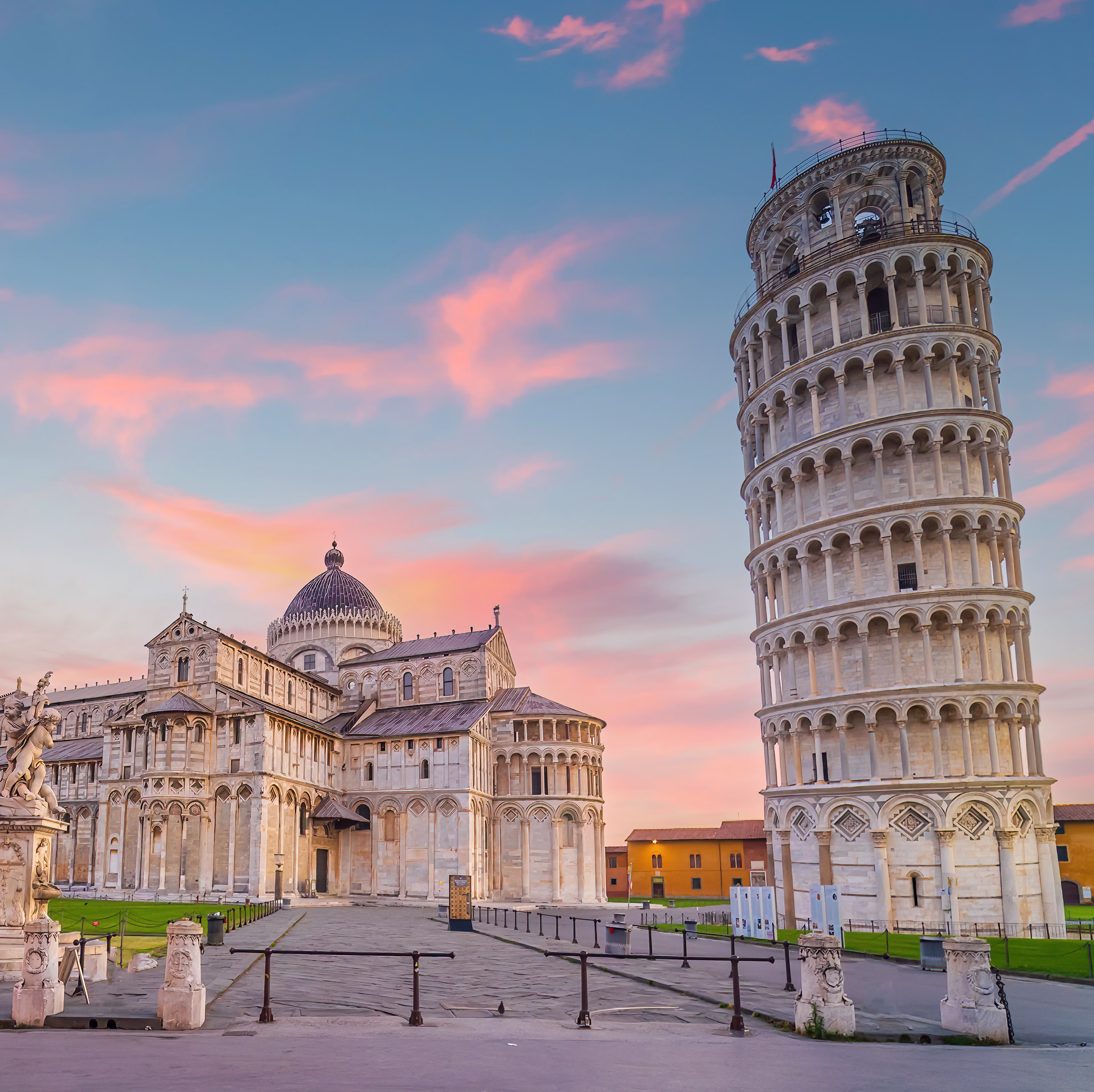 The Leaning Tower of Pisa and Pisa Cathedral against a vibrant pink and blue sunset sky.