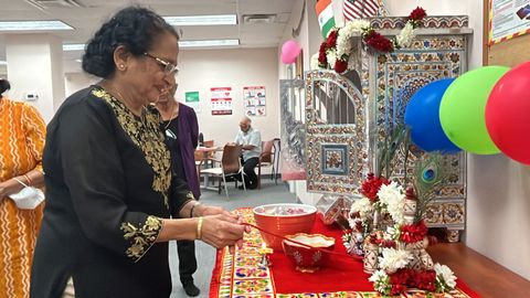 A participant makes an offering at a puja during Jupiter's Janmasthami celebration.