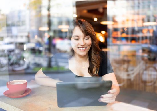 Eine Mitarbeiterin arbeitet mit einem Tablet in einem Café