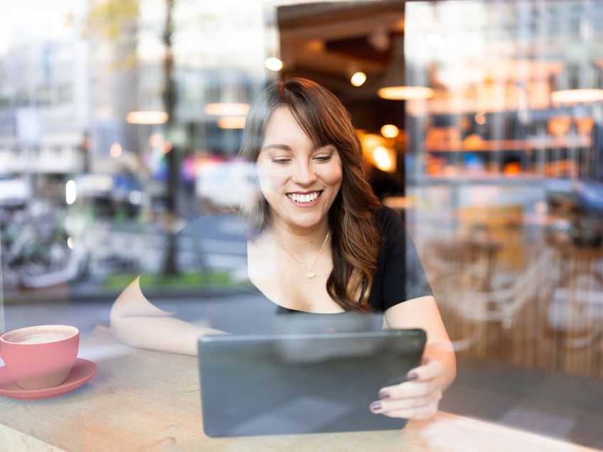 Mitarbeiterin arbeitet mobil mit einem Tablet in einem Café