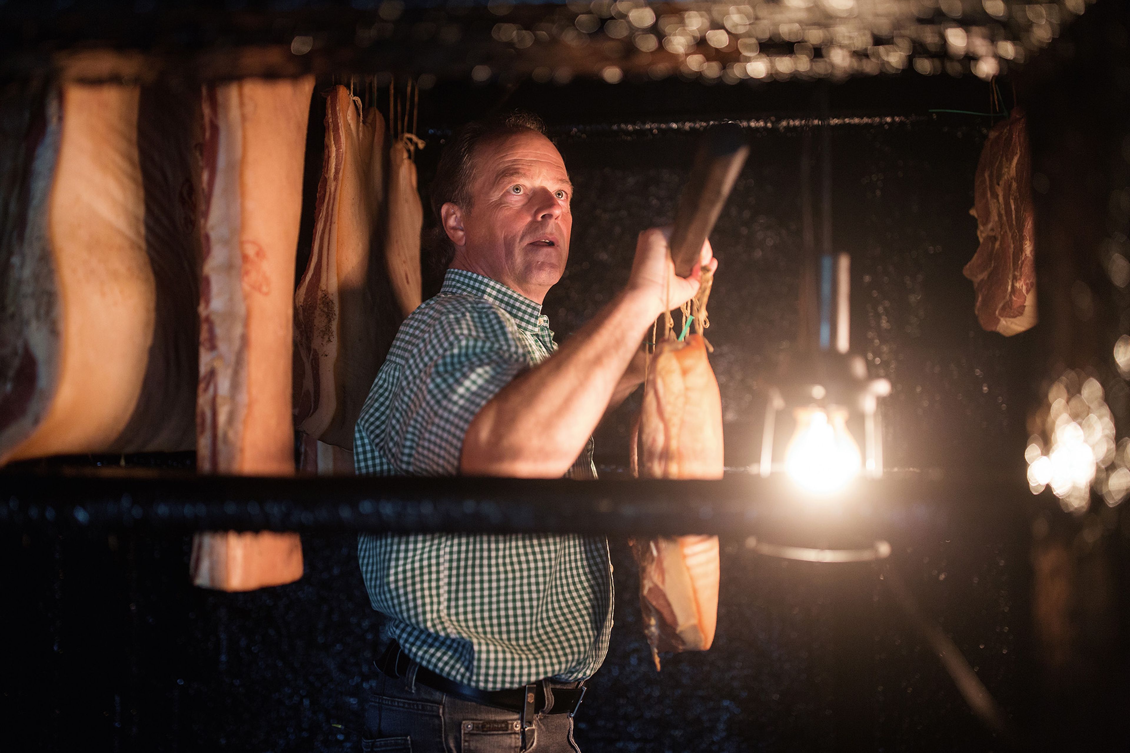 Hans Steinwender im Räucherkeller am Aufhängen des Speckes