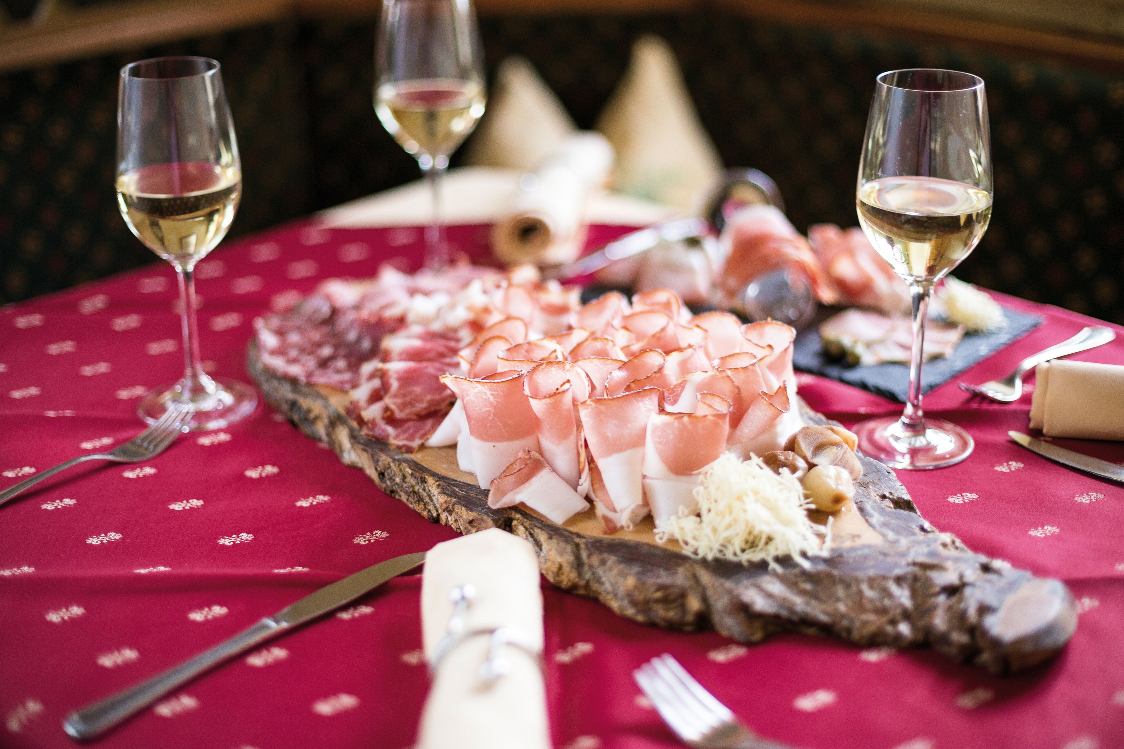 Ein gedeckter Tisch mit Speck und Wein.
