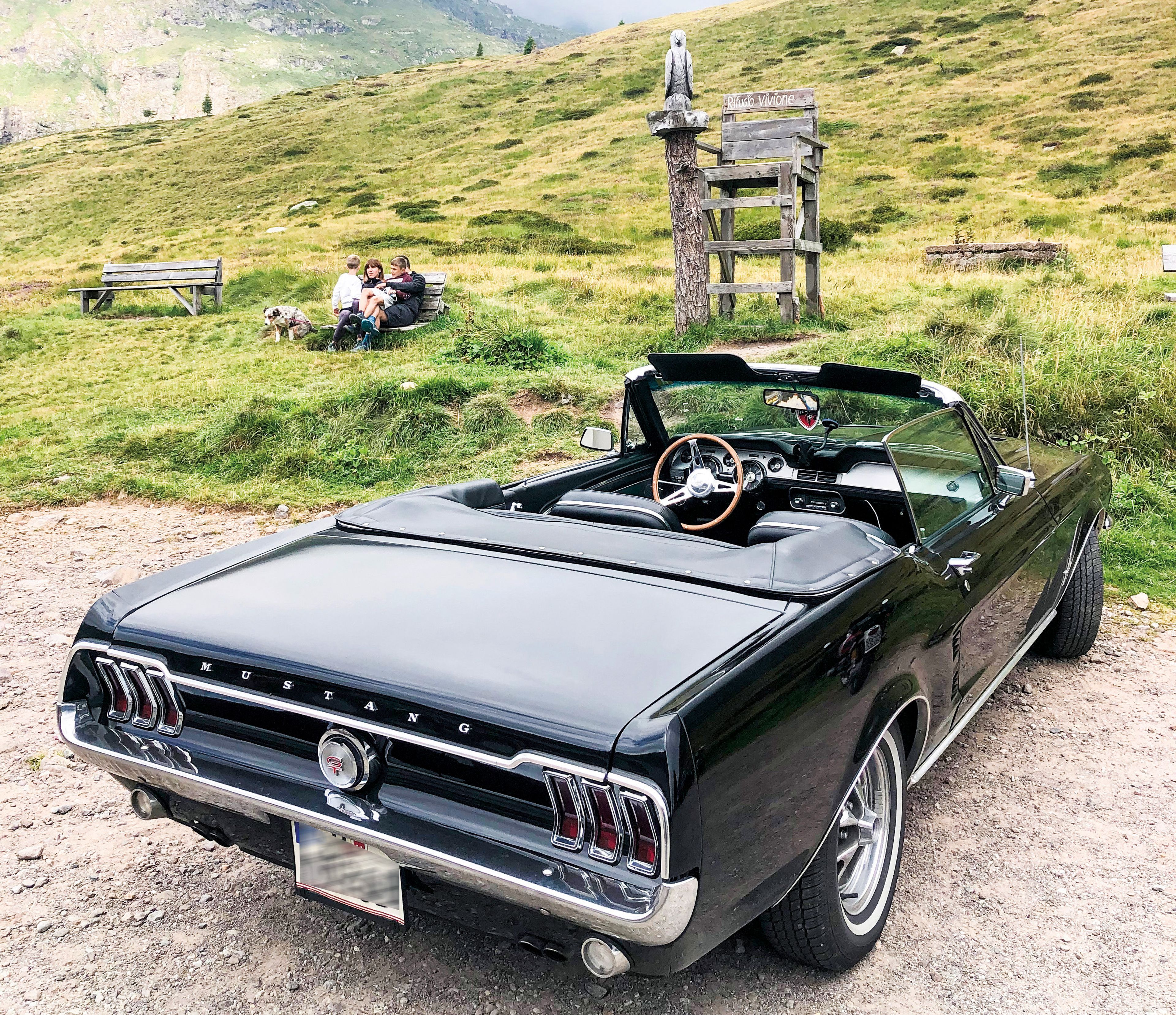 Schwarzer Mustang-Cabrio Oldtimer parkt im grünen auf einem Rastplatz