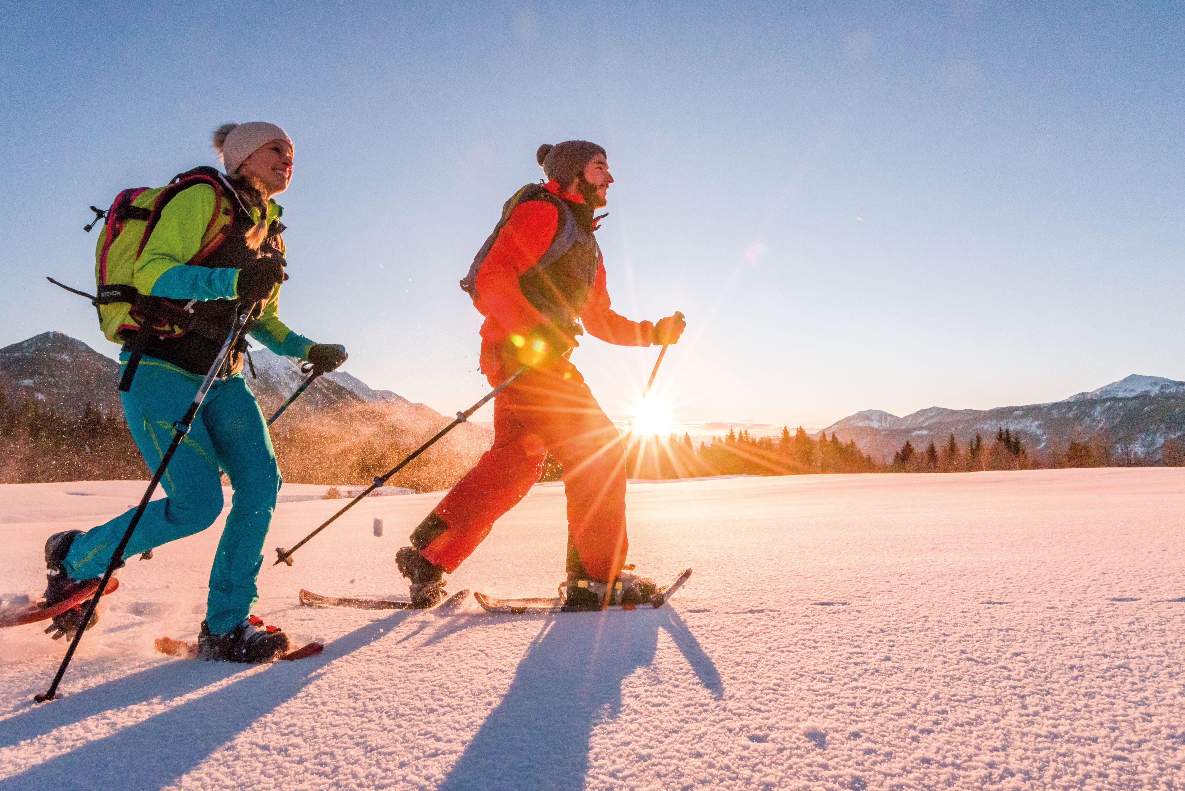 Zwei Personen die währen des Sonnenuntergangs Schneeschuhwandern