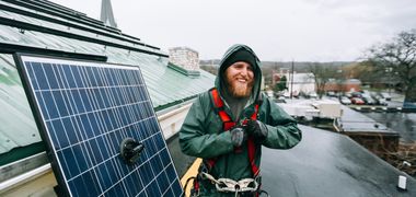 Ein Handwerker installiert ein PV Panel auf einem Dach.