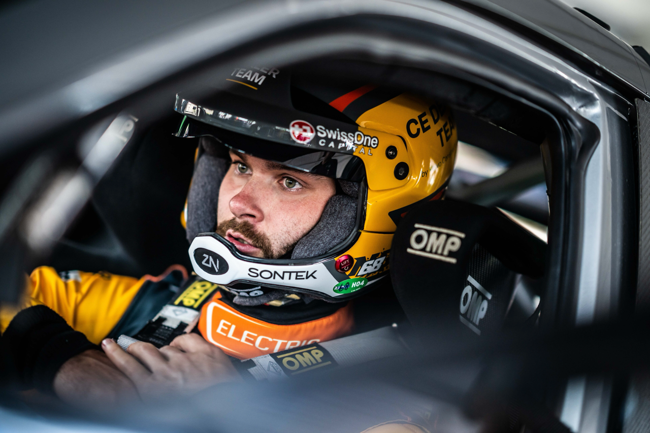 Rallycross driver Niclas Grönholm sits in his racing car wearing an open-face helmet