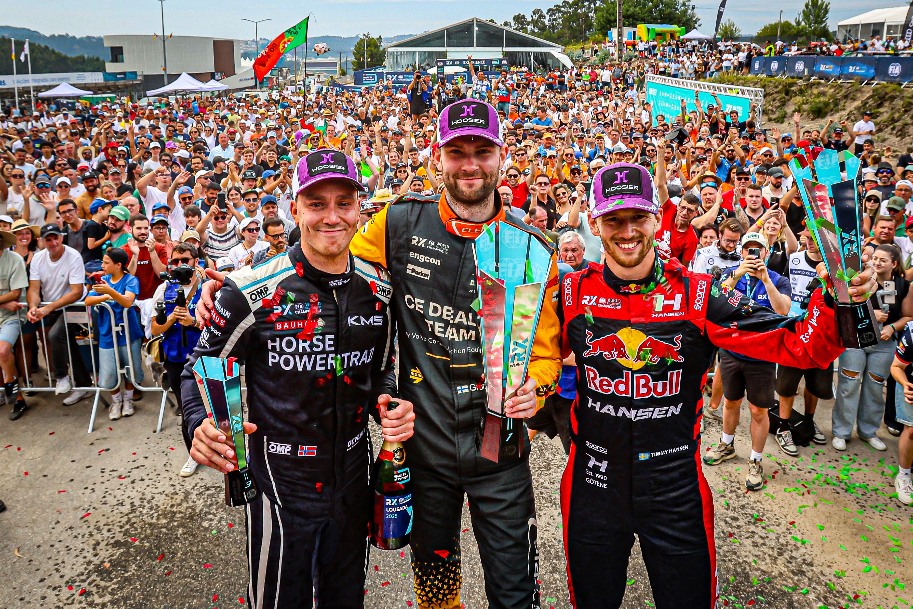 drivers on a podium in front of a massive crowd