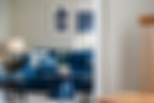 Eine blaue Couch und blauer Tisch vor einer hellen Wand mit gerahmten Bildern.