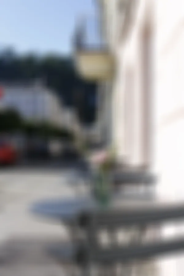 Two-person-tables outside of a hotel on the pavement
