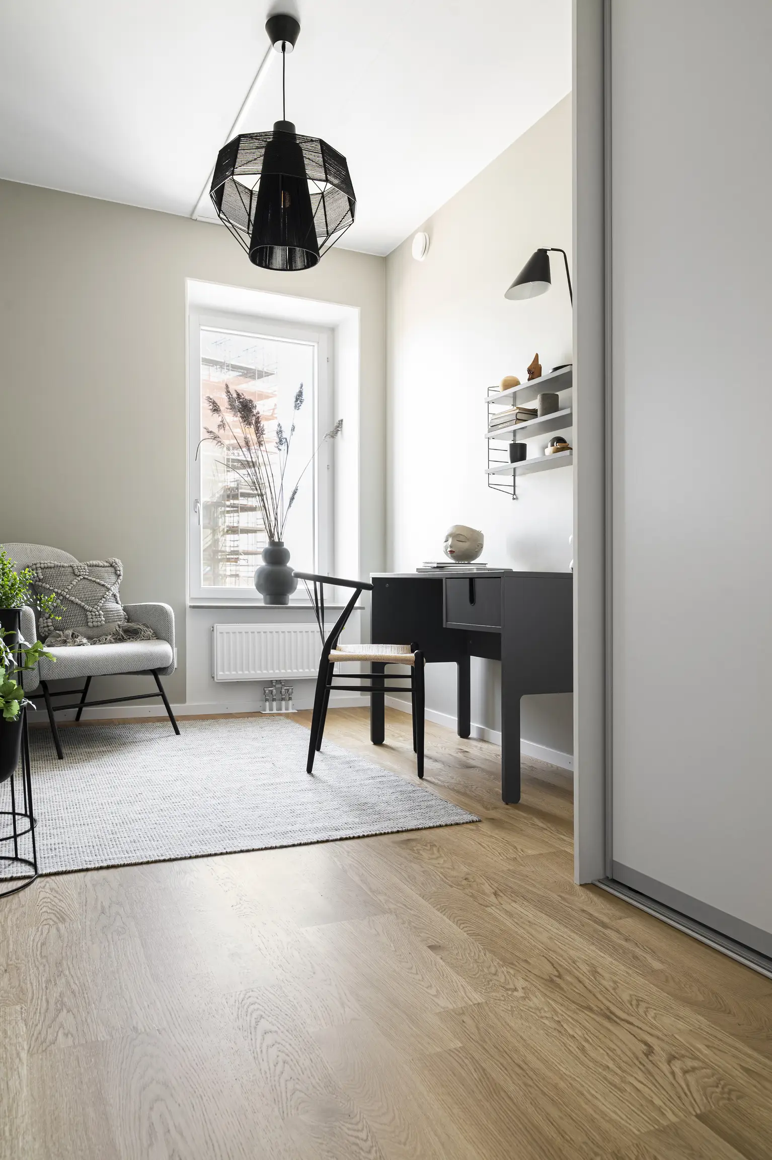 A cozy home office with a light, natural-toned wooden floor, complemented by minimalist furniture and a touch of greenery for a serene ambiance.