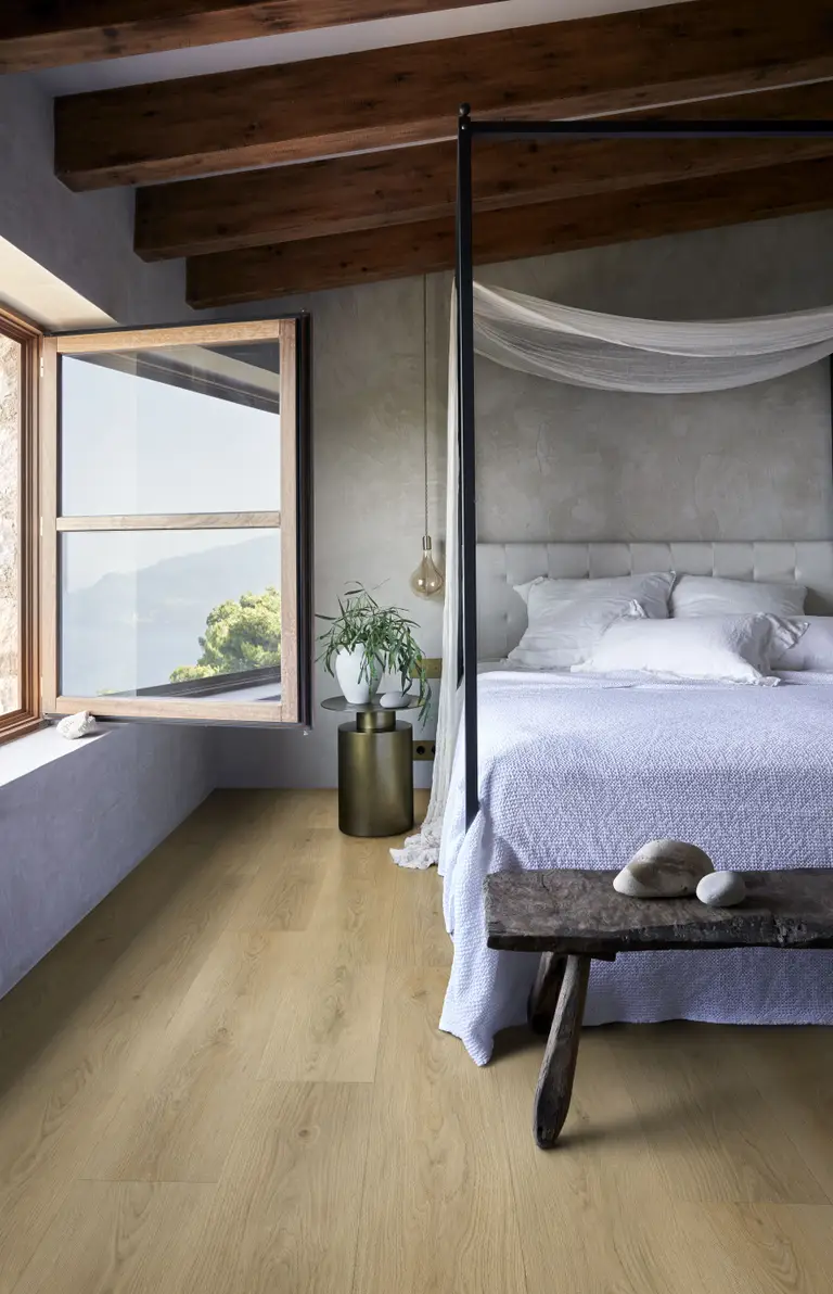 Cozy bedroom with a canopy bed, white bedding, wooden bench, and large open window with a scenic view. Modern decor and wooden beams.