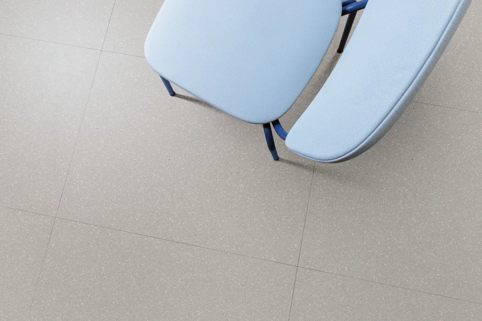 Overhead view of two light blue cushioned seats on a gray tiled floor, with one seat slightly separated from the other.