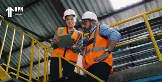 Profesionales en un almacén analizando estrategias de supply chain management con una tableta.