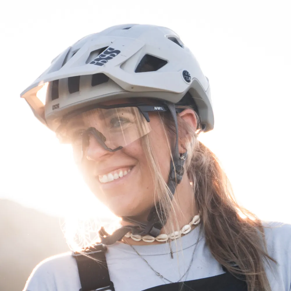 Lächelnde Fahrerin mit Helm und Sonnenbrille im Gegenlicht
