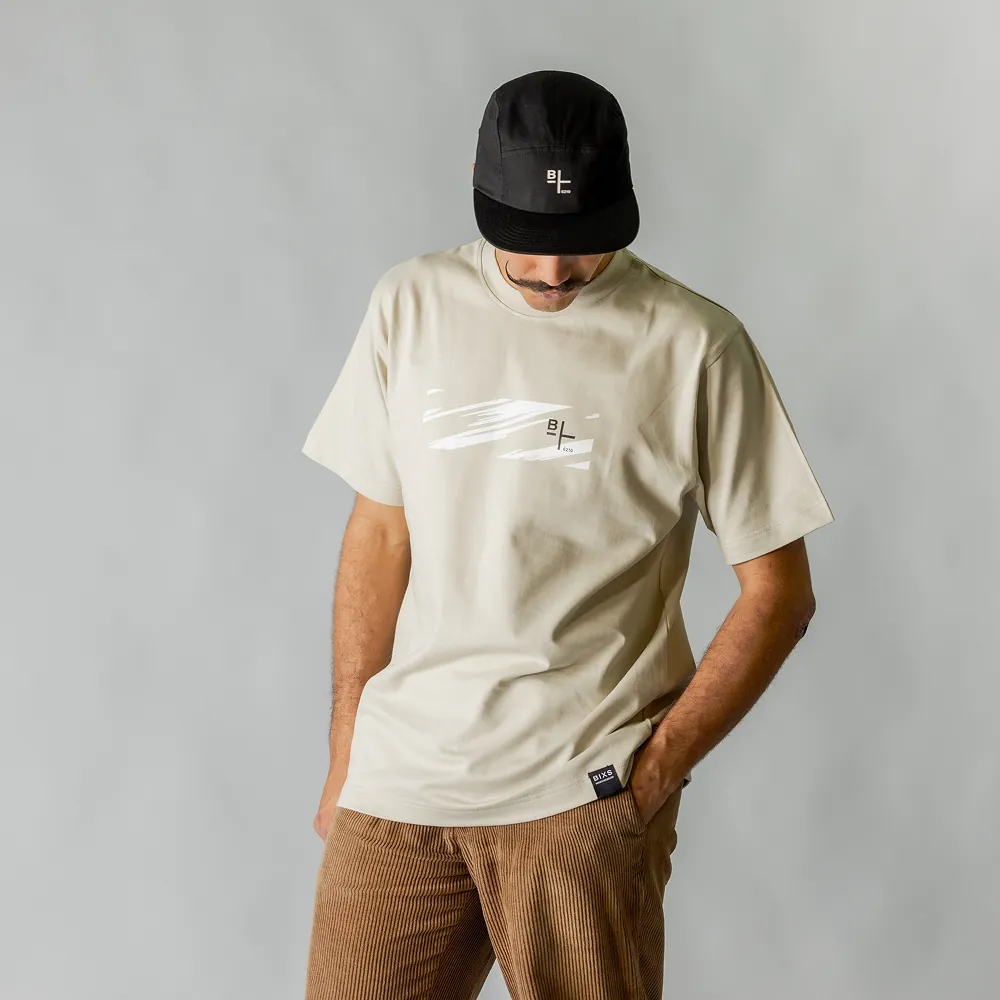 Beiges T-Shirt mit BIXS Markendruck und schwarzer Cap, Model blickt nach unten