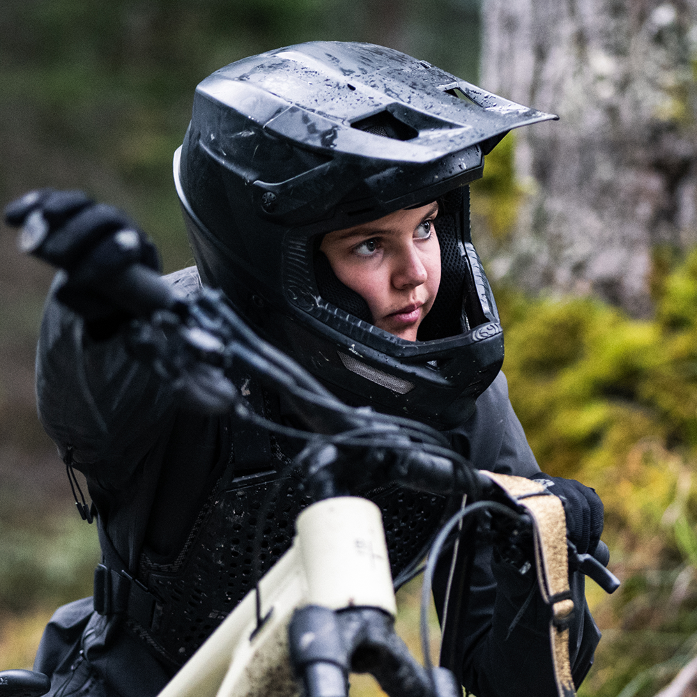 Nahaufnahme eines Kindes der BIXS Traction Crew mit Fullface-Helm auf dem Mountainbike