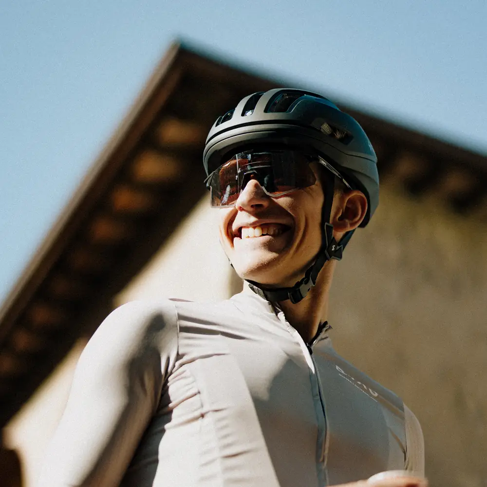 Lächelnder Fahrer mit Helm und Sonnenbrille vor Hausgiebel