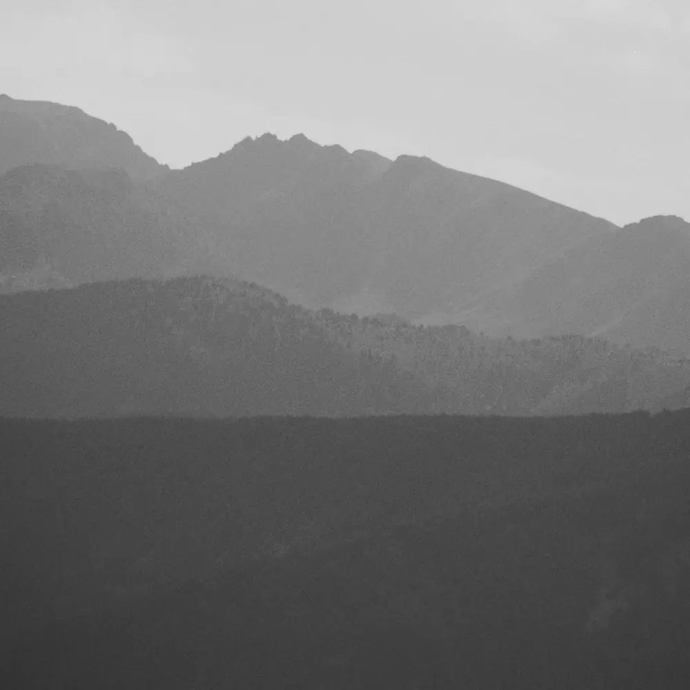 Schwarz-weiss Silhouette einer Bergkette im Dunst, mehrere Geländestufen im Vordergrund