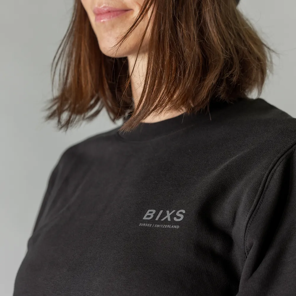 Detailaufnahme des BIXS Schriftzugs auf schwarzem Sweater am Ausschnitt