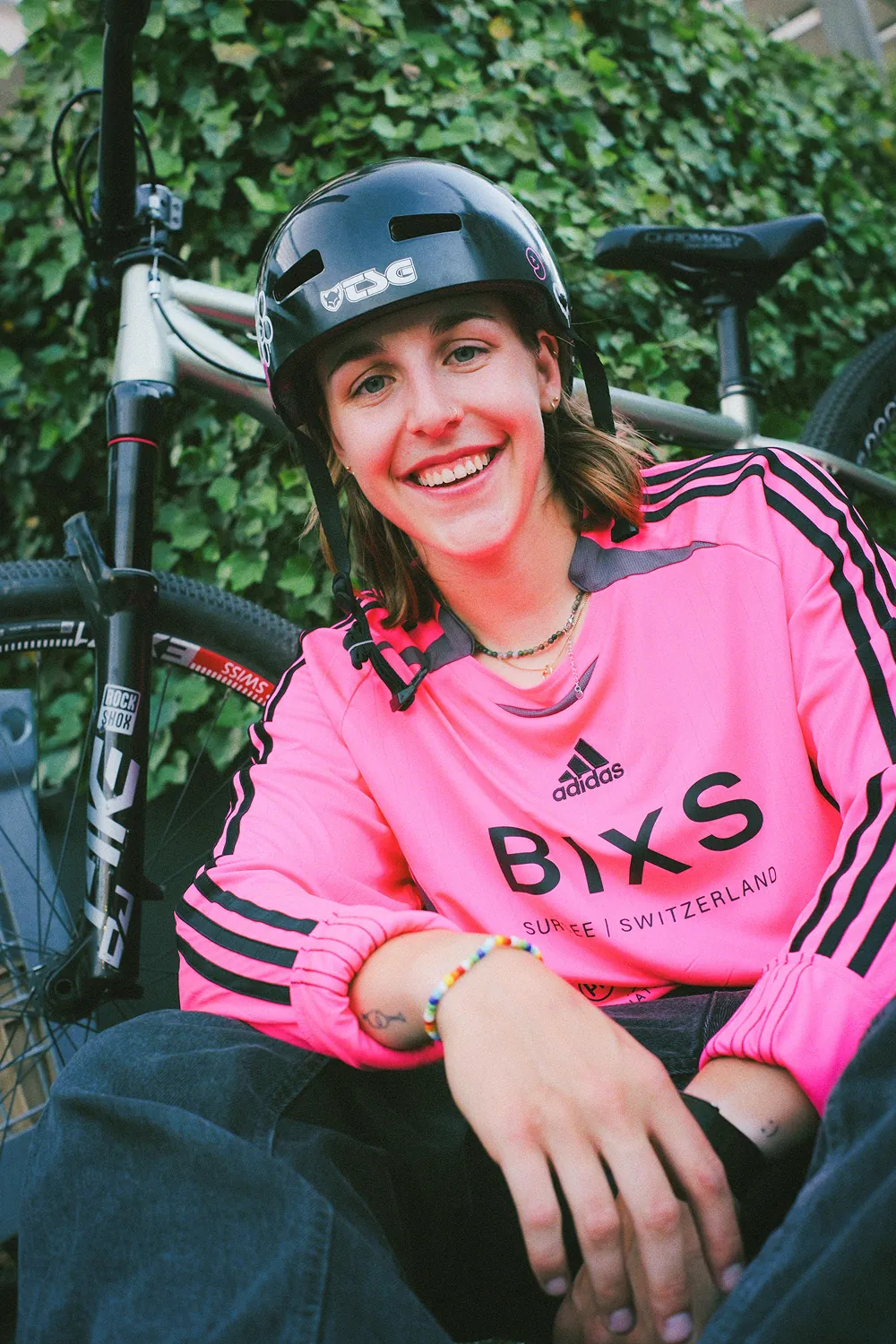Michelle Neuner, BIXS Mindsetter, im pinken BIXS Trikot mit BMX-Helm, lachend neben ihrem Bike