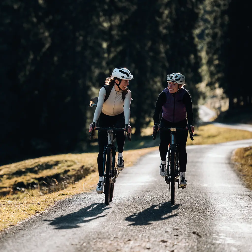 Zwei lachende Fahrerinnen auf BIXS Gravel-Bikes auf kurviger Passstrasse