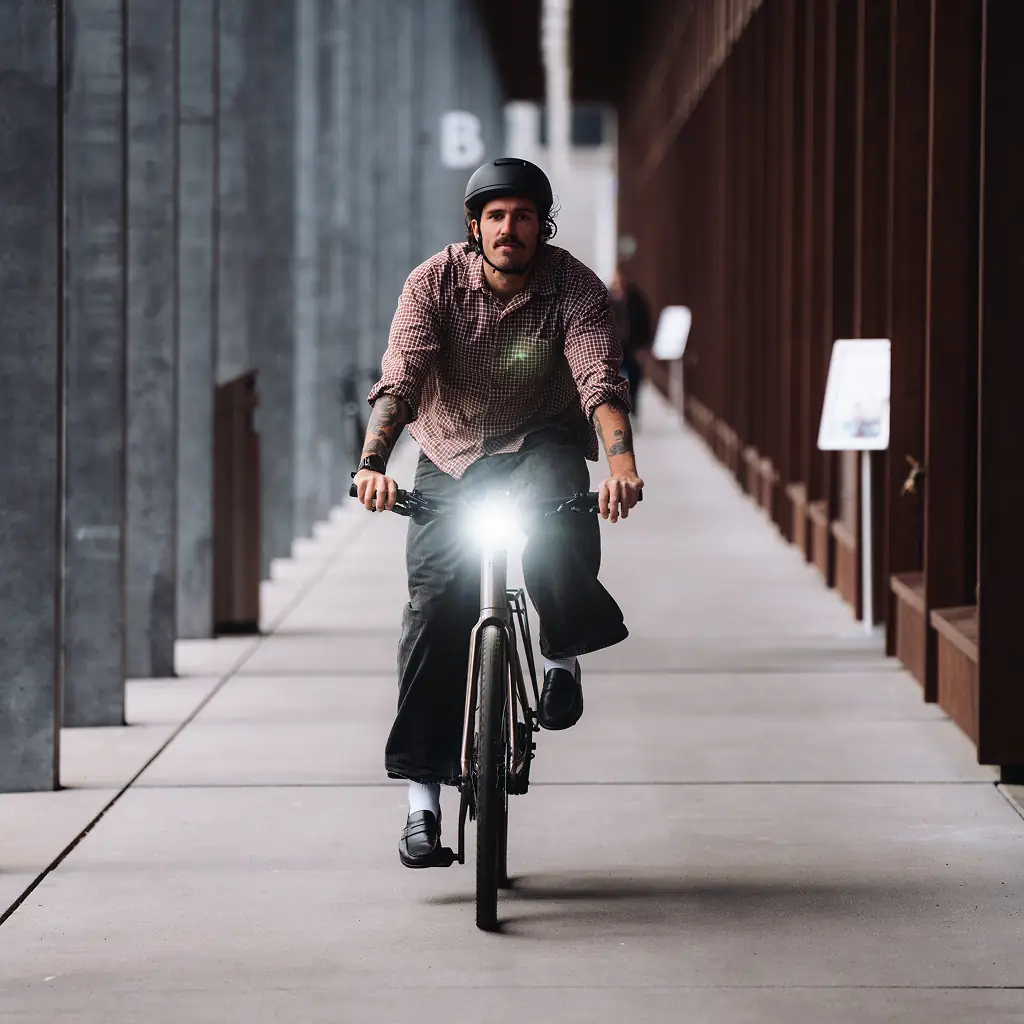 BIXS E-Bike-Fahrer mit eingeschaltetem Licht in modernem Betonkorridor