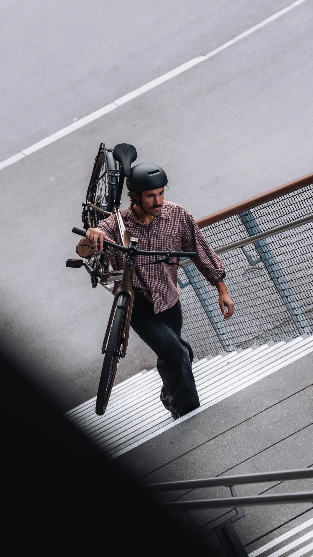 Mann trägt sein Urban Bike eine Treppe hinauf in der Stadt