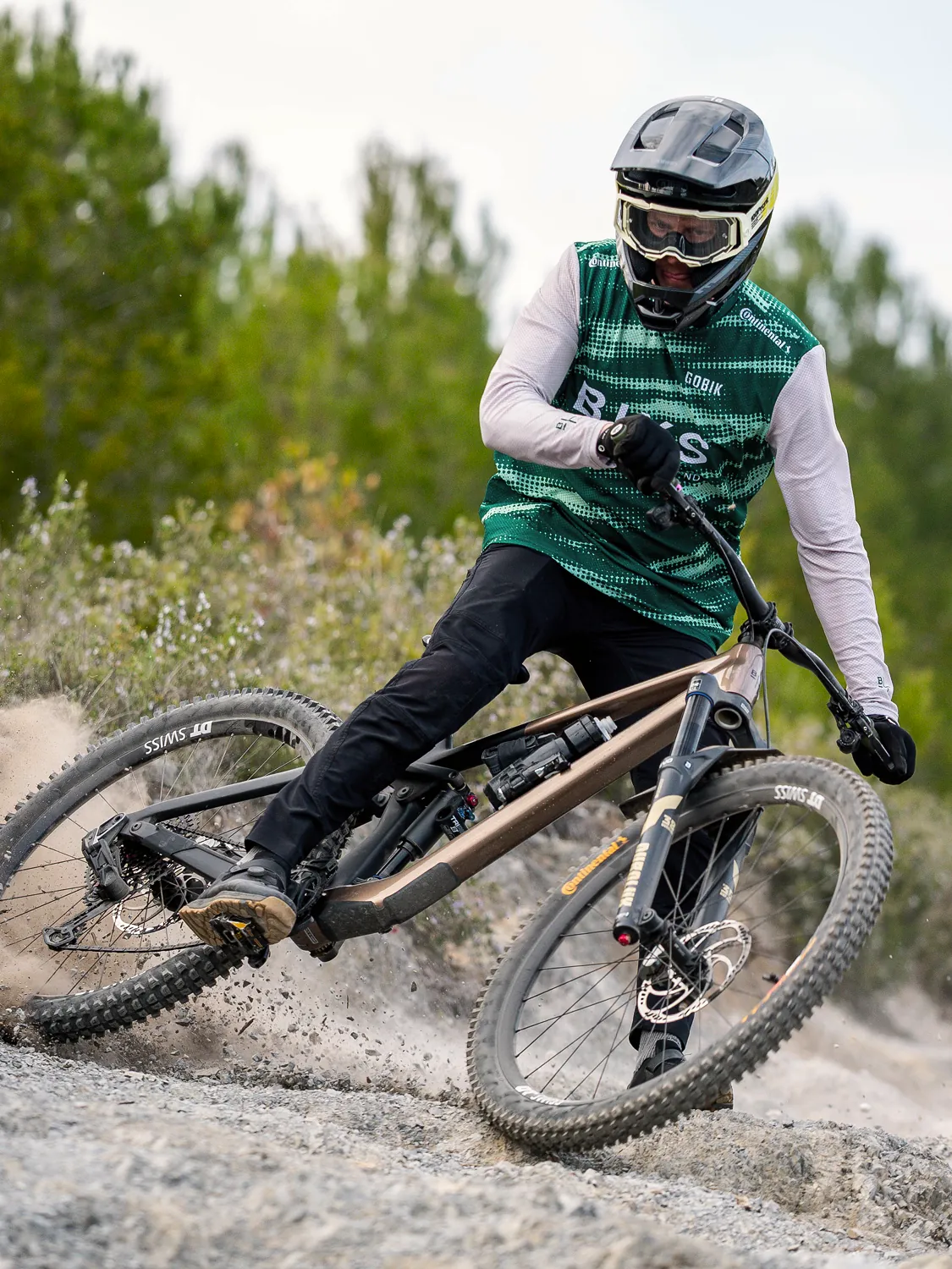 BIXS Race Team Fahrer in grün-weissem Trikot durchfährt staubige Anliegerkurve auf BIXS Lane Enduro-Bike