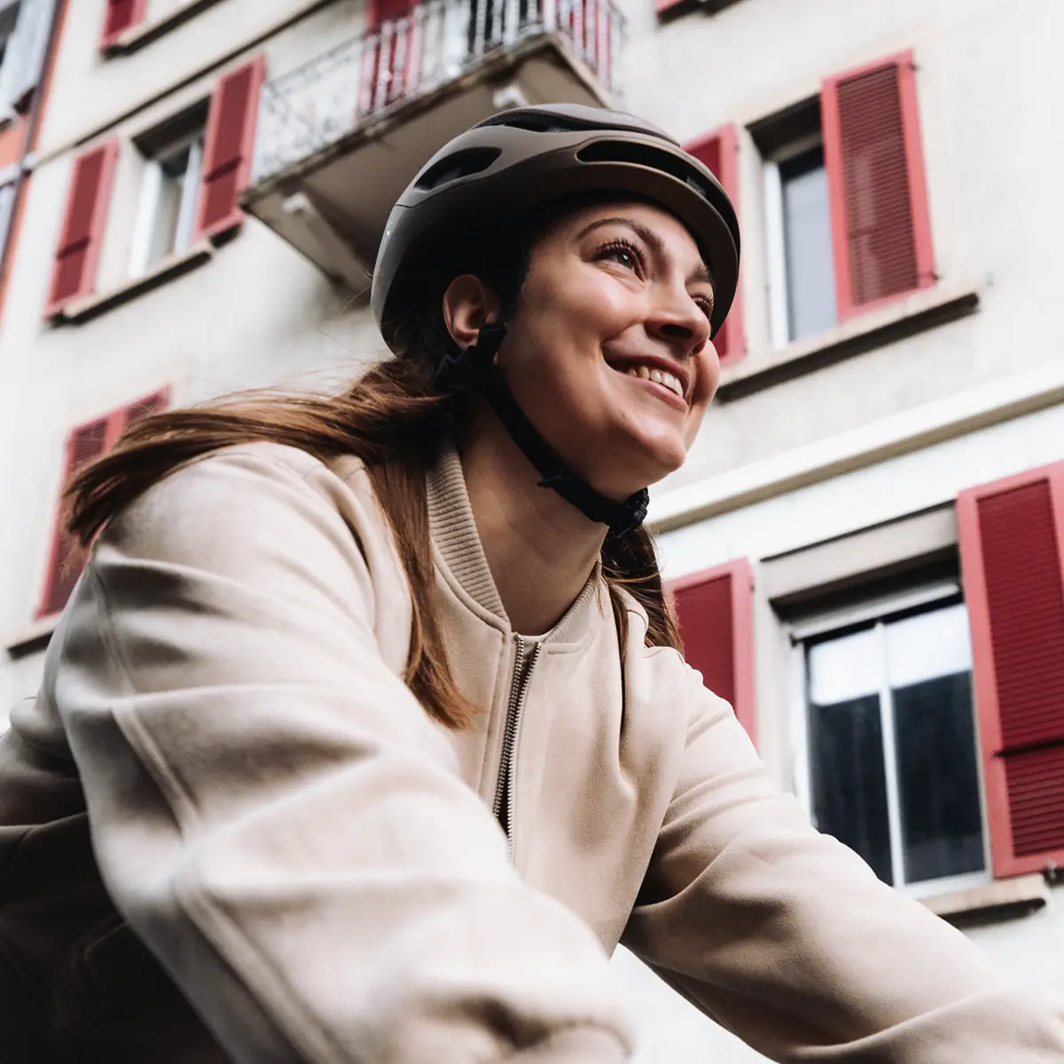 Lächelnde Fahrerin mit Helm vor Hausfassade mit roten Fensterläden, BIXS District Kontext