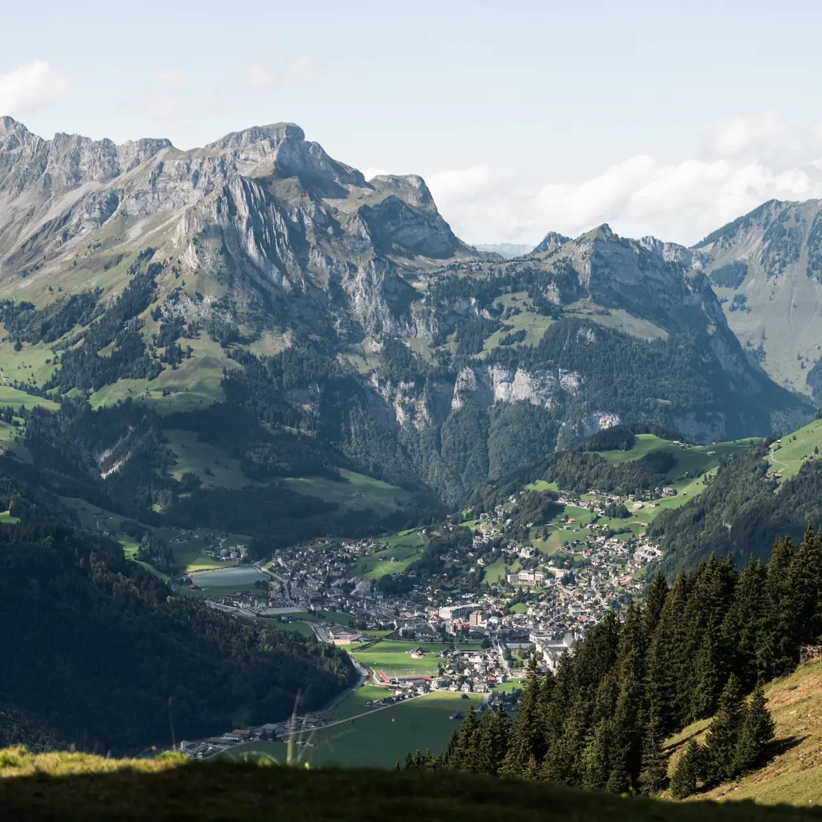 Blick von oben auf ein Schweizer Alpental mit Bergdorf zwischen schroffen Gipfeln