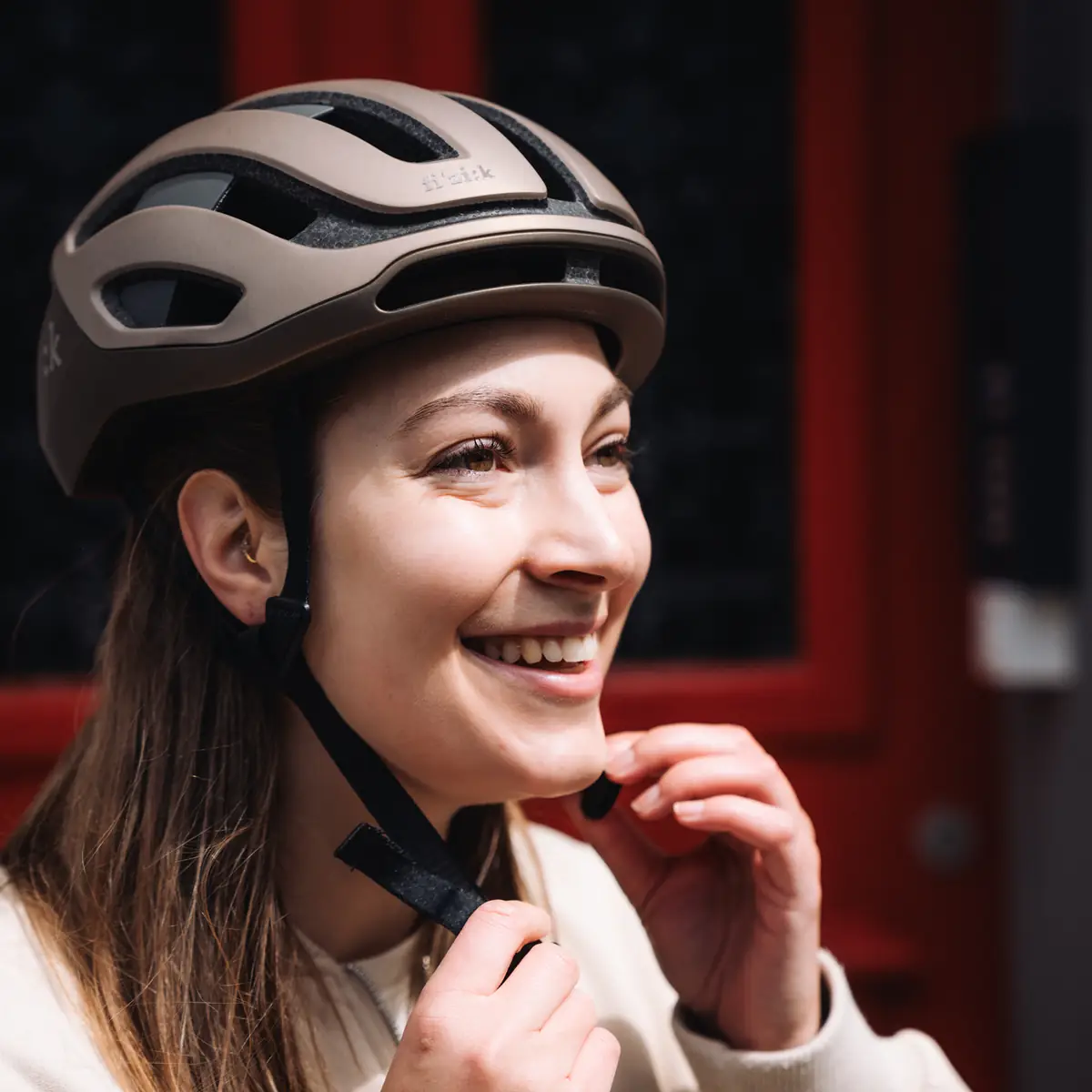 Lächelnde Fahrerin schliesst den Verschluss ihres Fahrradhelms