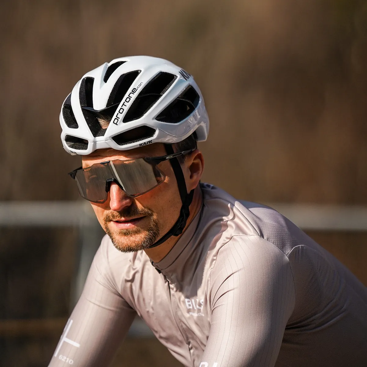 Nahaufnahme eines Rennradfahrers mit weissem Helm und verspiegelter Sportbrille