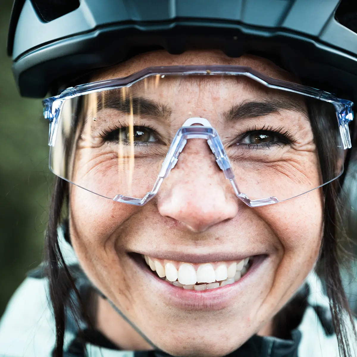 Extreme Nahaufnahme einer lachenden Fahrerin mit Helm und Schutzbrille