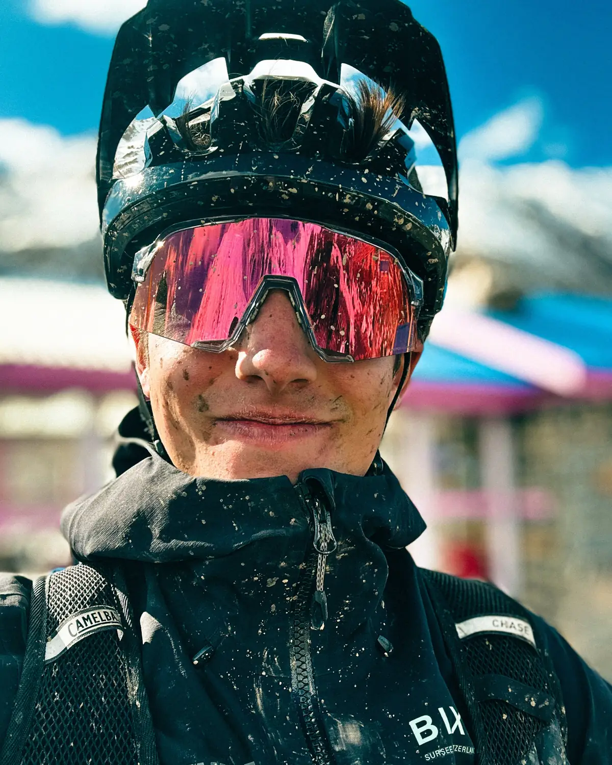 Nahporträt eines staubverschmierten Fahrers mit verspiegelter Brille und Helm