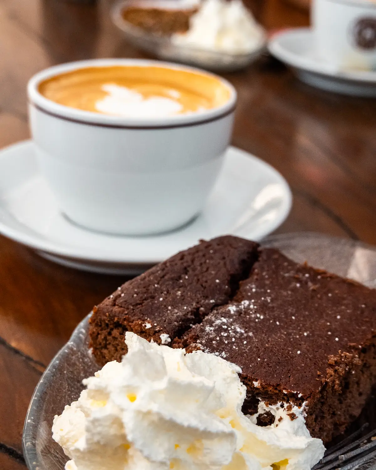 Cappuccino und Schokoladenkuchen mit Rahm auf Holztisch