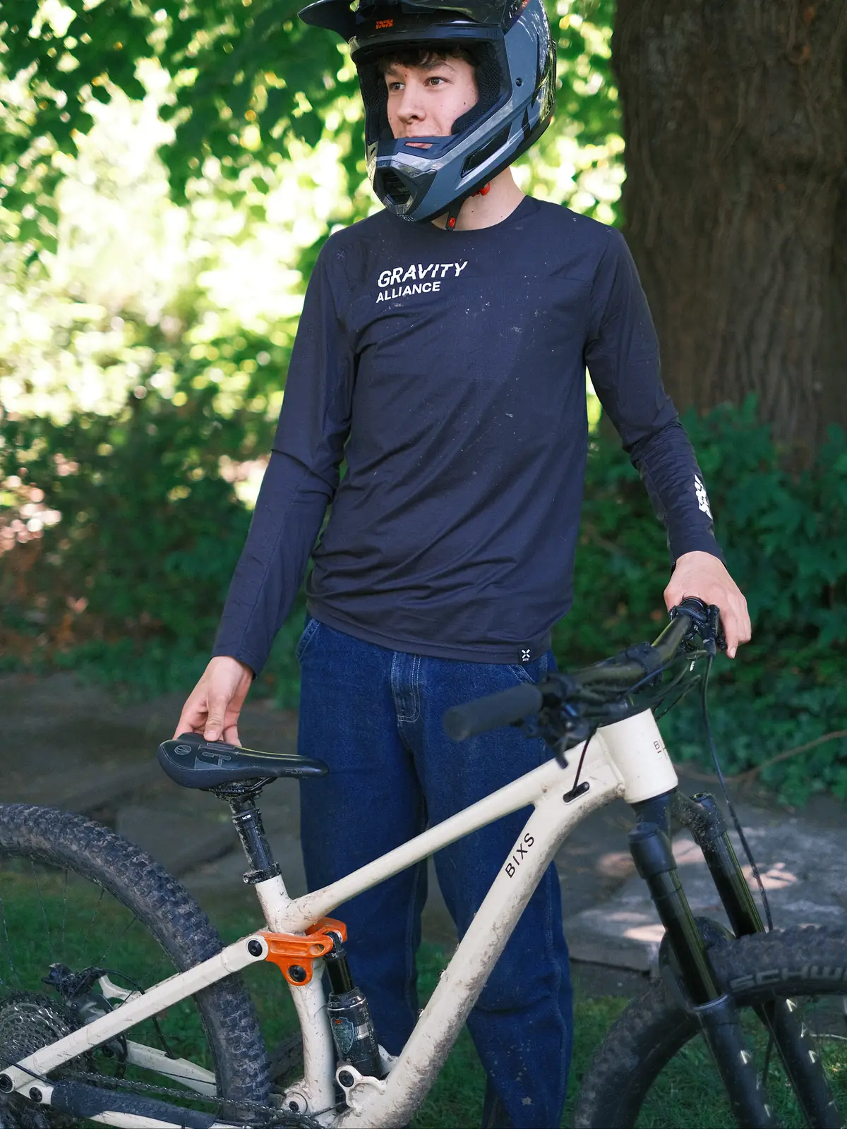 David mit Fullface-Helm und "Gravity Alliance" Shirt steht neben seinem BIXS Dirt-Bike im Garten
