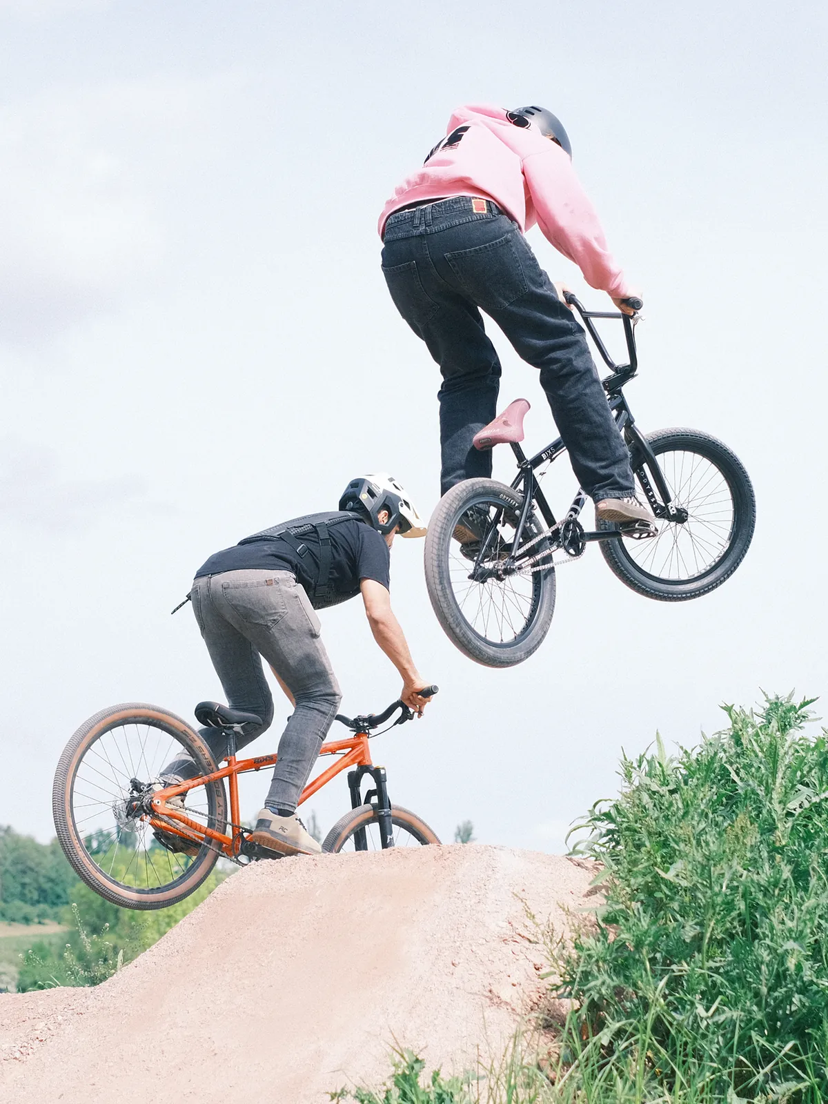 Zwei Fahrer springen mit BIXS Stomp BMX-Rädern über einen Dirt-Jump